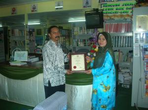 Pn. Yana bt Mohd Kamal menyerahkan Sijil Penghargaan Penggunaan Sistem e-Waktu kepada En. Hakmat.